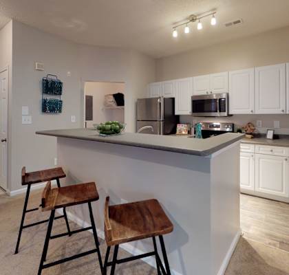 a kitchen with a large island with two stools in front of it at Autumn Park Apartments, Charlotte, NC, 28262