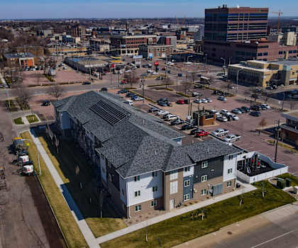 A parking lot with cars and a building with a grey roof.