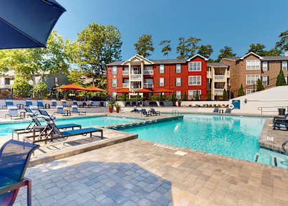 A swimming pool surrounded by lounge chairs and umbrellas in a residential area.