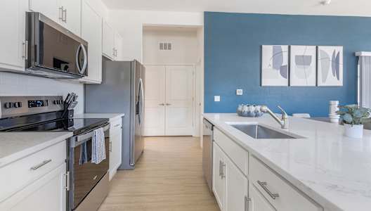 A modern kitchen with white cabinets and a blue wall.