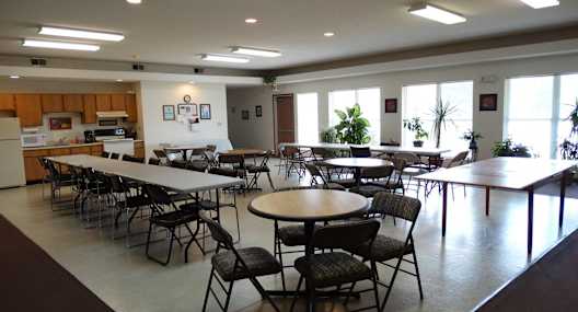 a dining room with tables and chairs and a kitchen