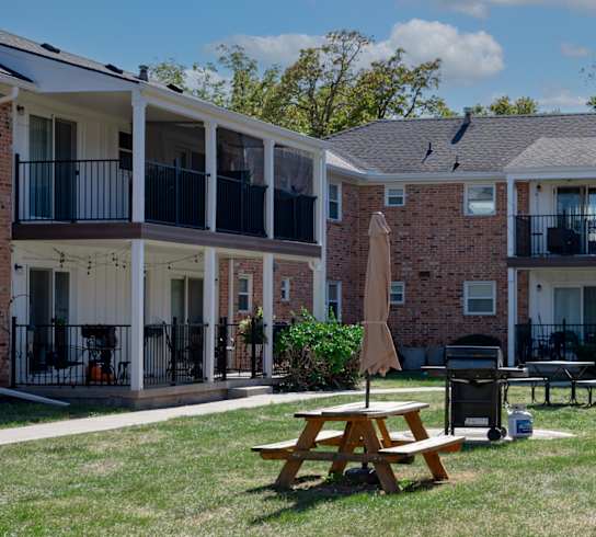 A sunny day at a brick apartment complex with a picnic table in the foreground.