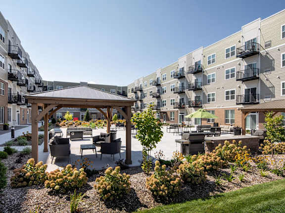 A sunny day at a residential complex with a gazebo and well-maintained gardens. at The Edison at Rice Creek I and II, Minnesota, 55126