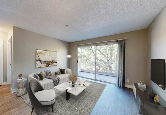A living room with a grey couch and a painting on the wall.