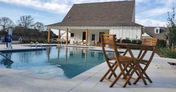 a pool with chairs and a house in the background