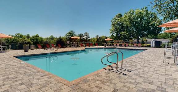 A swimming pool surrounded by a brick patio and trees. at Vue on Medlock, Georgia