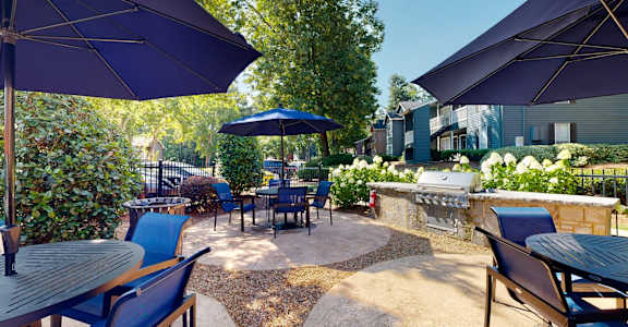 A patio with tables and chairs under umbrellas.