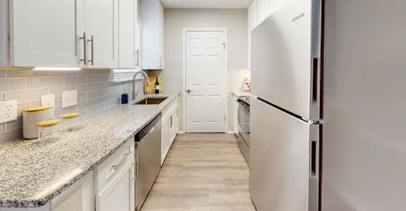 A kitchen with white cabinets and a granite countertop.
