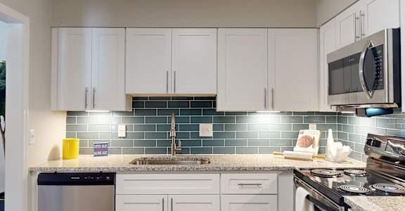 A kitchen with white cabinets and a black stove top oven. at Vinings RiverVue, Atlanta, GA