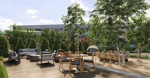A wooden deck with chairs and a table is surrounded by trees.