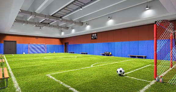 A soccer ball is on the ground in front of a red goal.