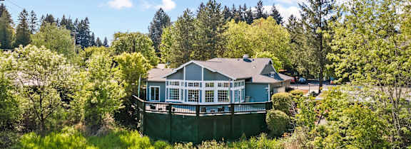 A house with a green fence surrounded by trees.