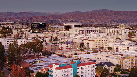 A cityscape with buildings of various colors and a mountain range in the background.