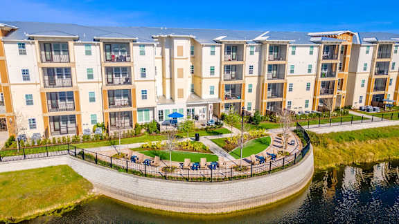 A large apartment complex with a pond in front.
