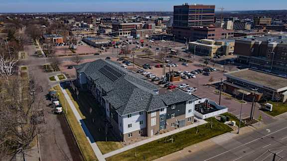 A parking lot with cars and a building with a grey roof.
