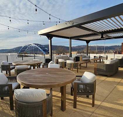 the deck on the water has tables and chairs and a pergola