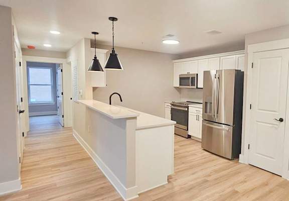 an open kitchen with a large island and a stainless steel refrigerator