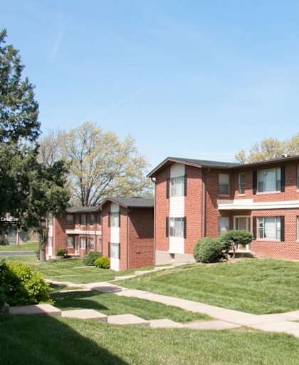 A red brick building with white windows and a green lawn in front.