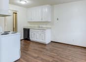 Thumbnail 7 of 8 - an empty kitchen with white cabinets and a counter top and a stove top oven