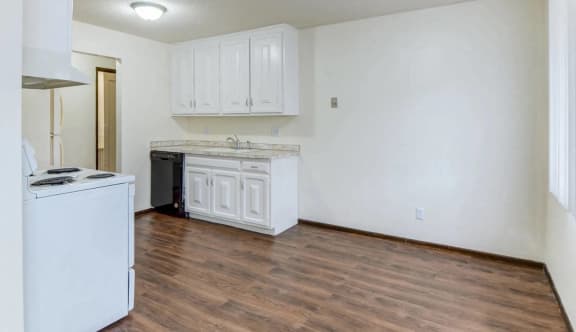 an empty kitchen with white cabinets and a counter top and a stove top oven