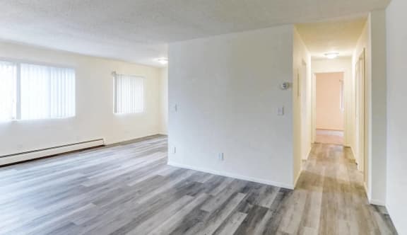 the living room and dining room of an empty apartment with wood floors and white walls