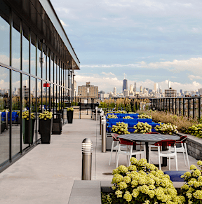 A patio with tables and chairs overlooking a city skyline. at Residences at Addison Clark, Chicago