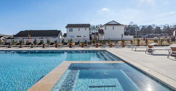 a shimmering blue swimming pool surrounded by a massive sundeck with lounge chairs at the clubhosue at Sanctuary at Indian Creek