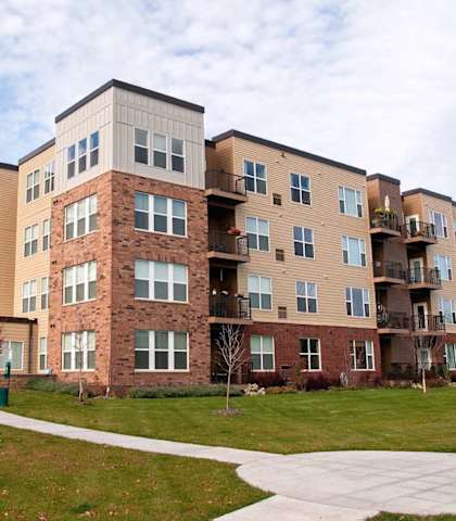 an exterior view of an apartment building with a walkway at The Cavanagh 55+ Apartments, Crystal, 55429