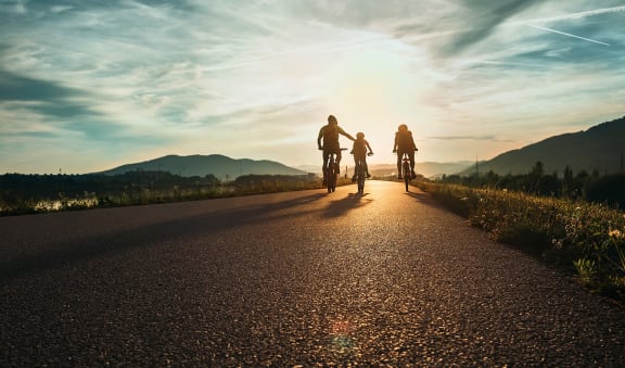 a group of people riding bikes on an empty road at sunset