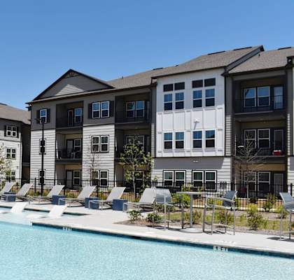 a swimming pool in front of an apartment building at Century Mundy Mill Apartments, Oakwood, GA 30566