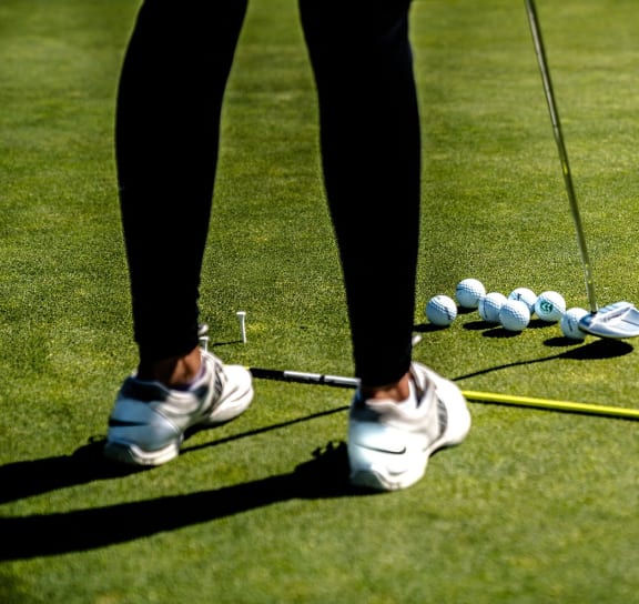 a person standing on a golf course with golf clubs