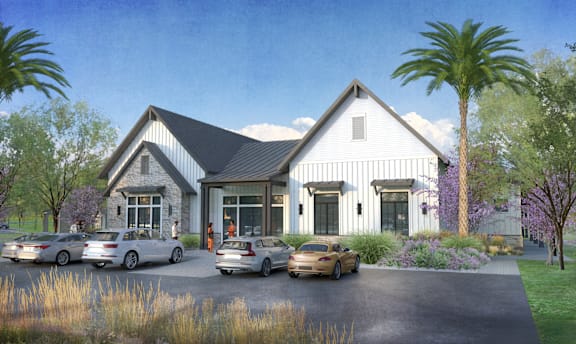A house with a black roof and white walls is surrounded by four cars.