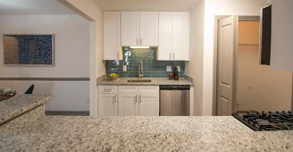 A kitchen with white cabinets and a granite countertop.