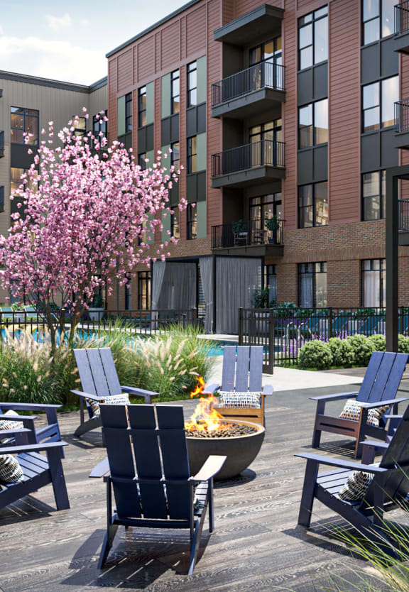 a fire pit and chairs on a patio in front of an apartment building
