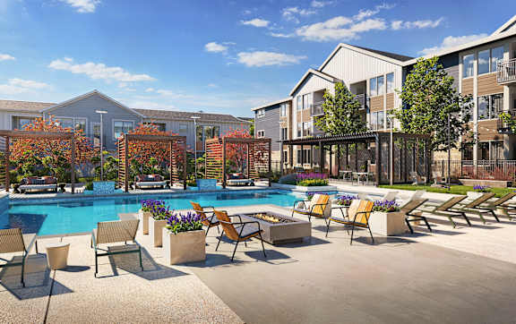 A pool surrounded by chairs and trees in front of apartment buildings.