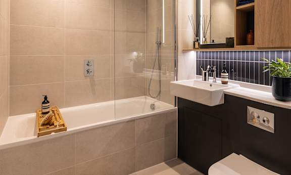 A modern bathroom with a white bathtub and a wooden tray on it.