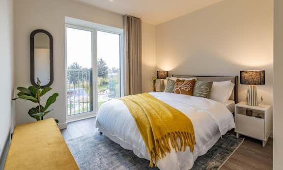 A bedroom with a large bed and a yellow blanket.
