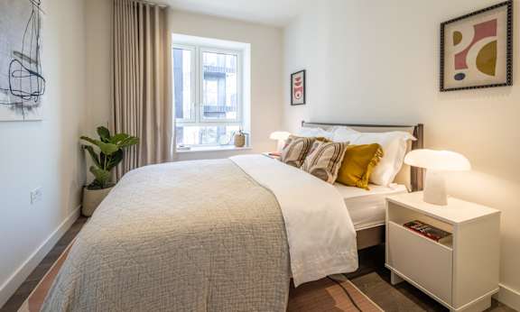A bedroom with a large bed and a window with curtains.