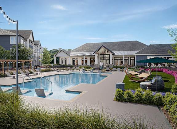 A large outdoor swimming pool surrounded by lounge chairs and umbrellas.