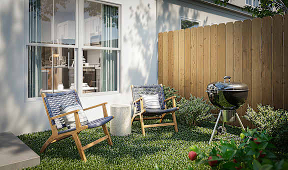 A backyard with a grill and two chairs.
