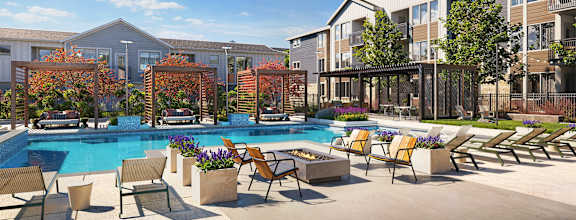 A pool surrounded by chairs and trees in front of apartment buildings.