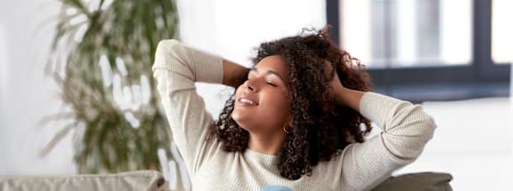A woman sitting on a couch with her hands behind her head