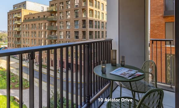 A balcony with a table and chairs overlooks a street.