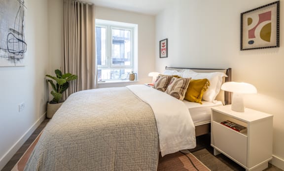 A bedroom with a large bed and a window with curtains.