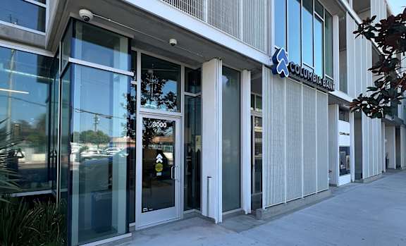 The image shows the front of a building with a glass door and a sign that reads "Columbia Bank."