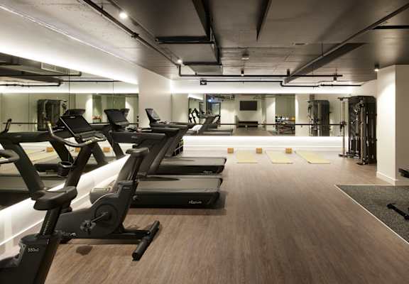 a gym with cardio equipment and weights on a wooden floor