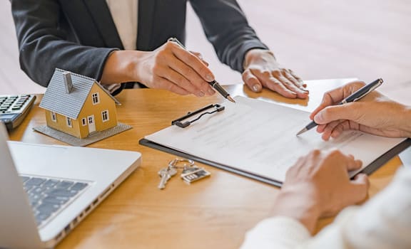 a group of people sitting at a table with papers and a house