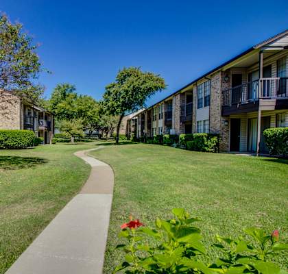 a walkway between two apartment buildings with grass and trees