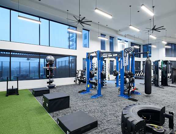 A gym with a variety of equipment including weights and a green artificial turf area.