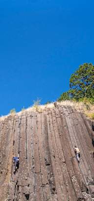 people climbing up a rock face with a blue sky in the background